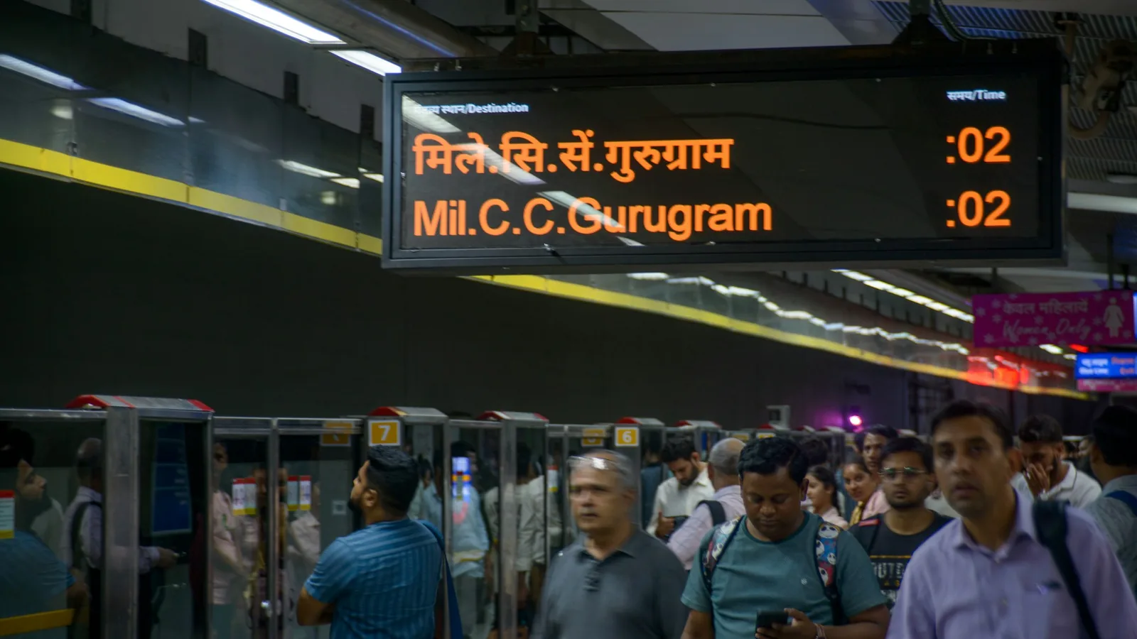 Passengers and a digital service display on a Delhi Metro platform